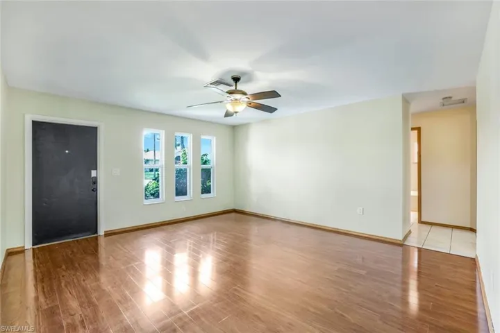 Empty room with baseboards, visible vents, ceiling fan, and light wood finished floors