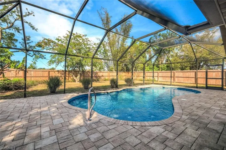 View of pool featuring glass enclosure, a patio, a fenced backyard, and a fenced in pool