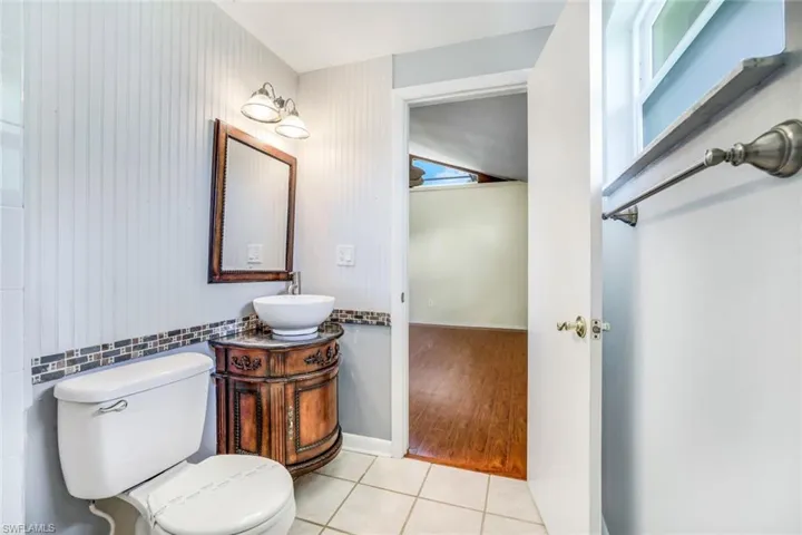 Half bath with tile patterned flooring, baseboards, vanity, and toilet
