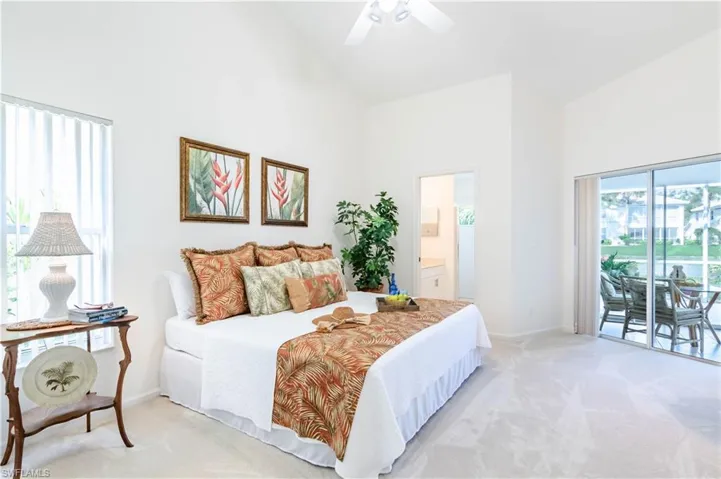 Carpeted bedroom with ceiling fan, ensuite bathroom, access to outside, and high vaulted ceiling