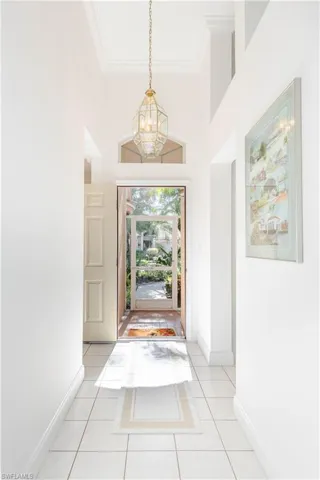 Tiled foyer with a towering ceiling, crown molding, and an inviting chandelier