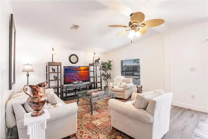 Living area featuring a ceiling fan and laminate wood finished floors, and lofted ceiling