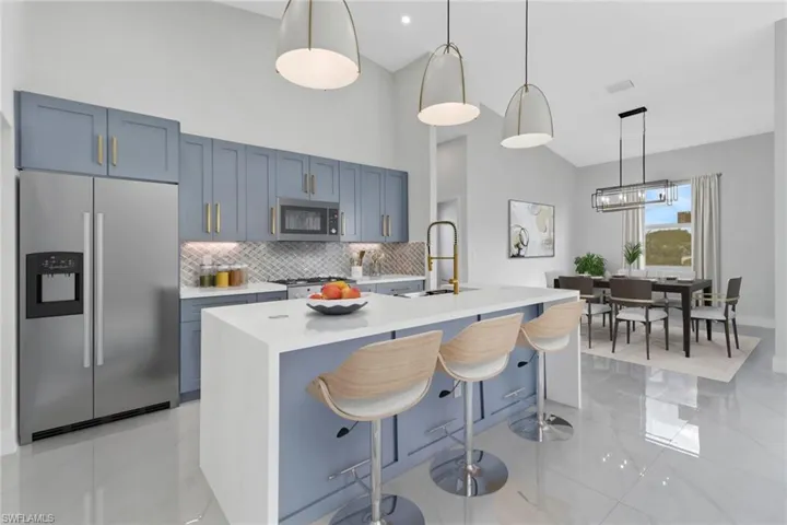 Kitchen with decorative light fixtures, a kitchen island with sink, appliances with stainless steel finishes, and sink