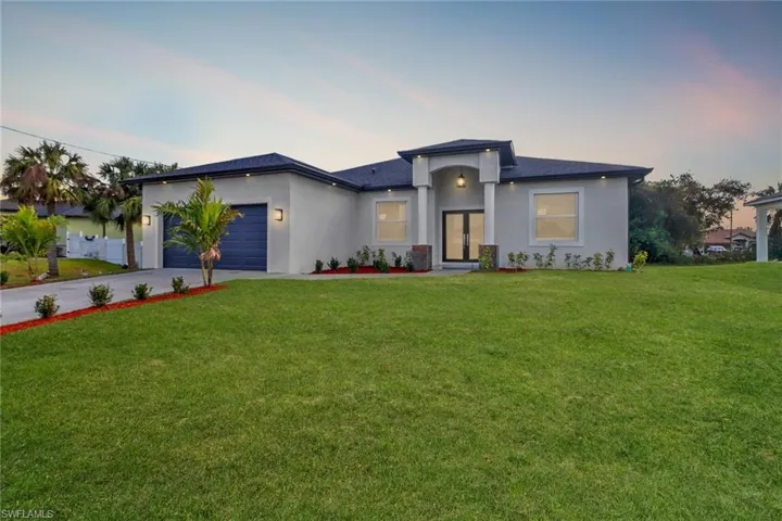 View of front of property with a garage and a lawn