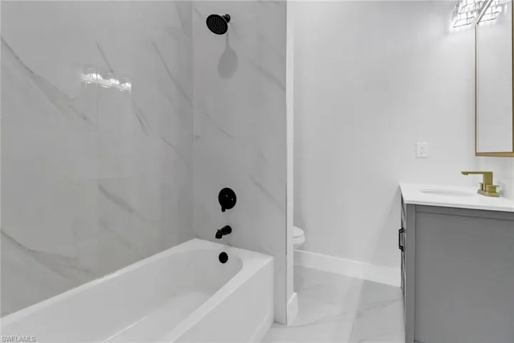 Full bathroom with tiled shower / bath combo, vanity, and toilet
