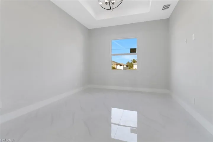 Empty room featuring a tray ceiling and a notable chandelier