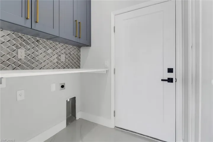 Washroom with light tile patterned floors, hookup for an electric dryer, and cabinets