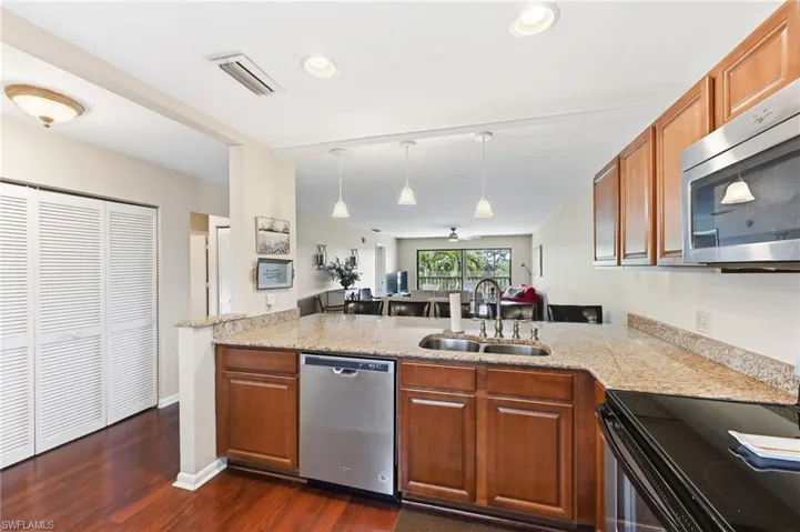 Kitchen featuring wood finish cabinetry, open floor plan, pendant lighting, and stainless steel appliances