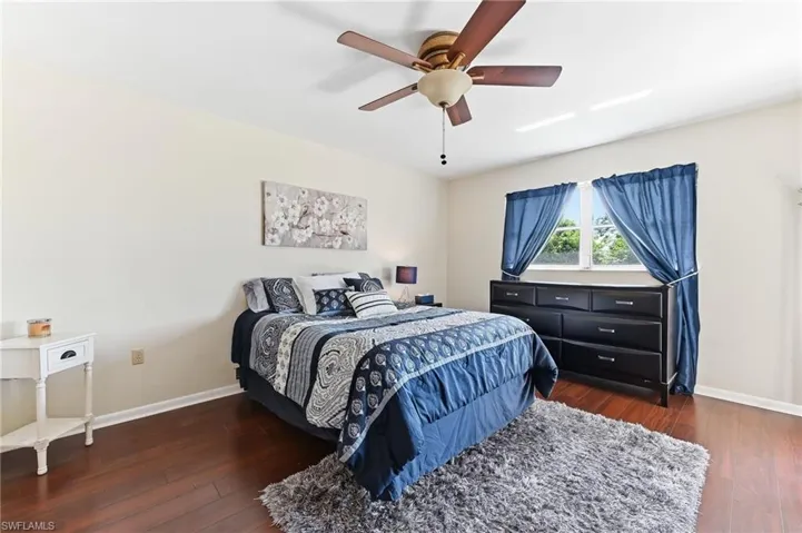 Primary suite with hardwood flooring and ceiling fan