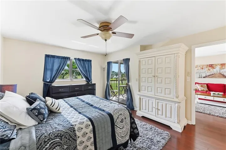 Primary suite with ceiling fan, hardwood flooring and direct access to screened lanai for seamless indoor-outdoor living.