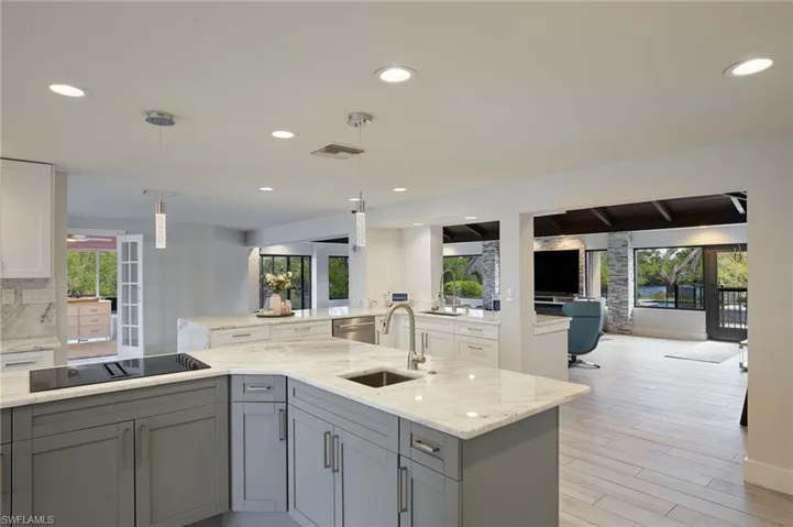 Kitchen featuring black electric stovetop, tasteful backsplash, gray cabinetry, open floor plan, and a sink