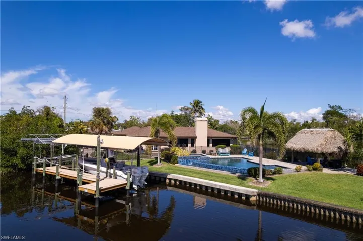 Dock area featuring a water view, boat lift, a fence, pool, and a yard