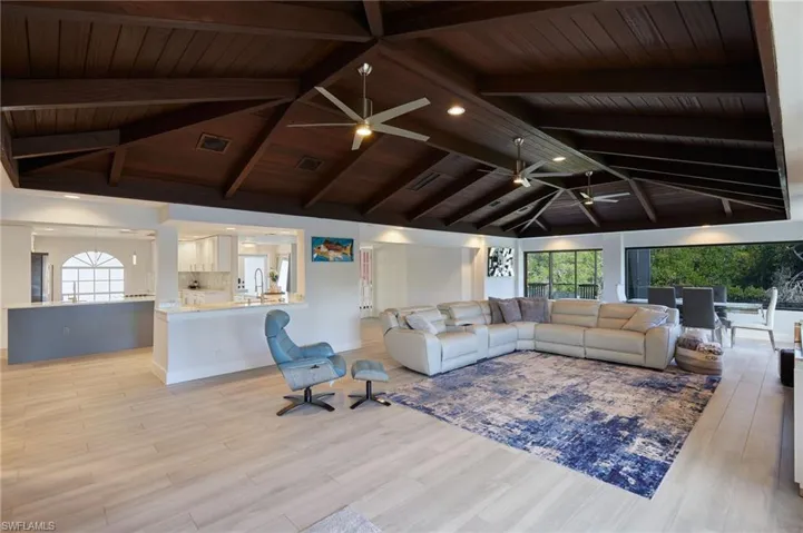Living area with vaulted ceiling with beams, a healthy amount of sunlight, visible vents, and ceiling fan
