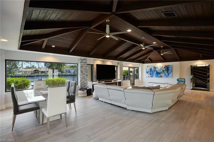 Living room with lofted ceiling with beams, wood ceiling, and a healthy amount of sunlight