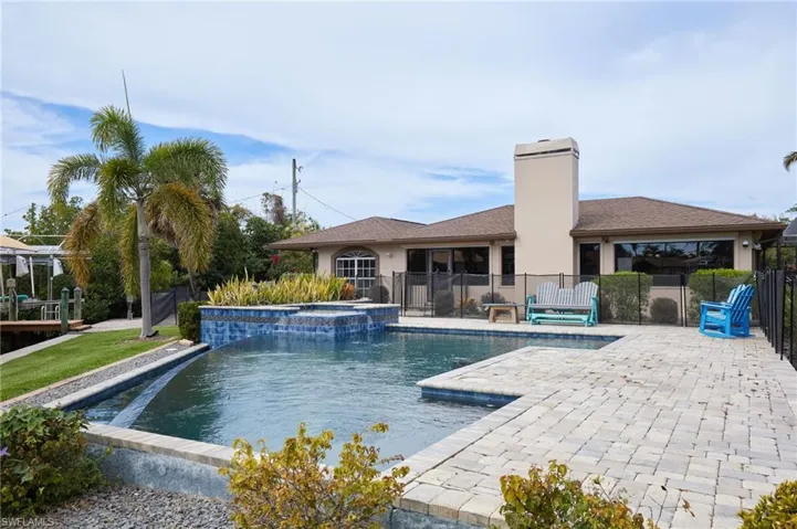 View of swimming pool with a pool with connected hot tub, fence, and a patio
