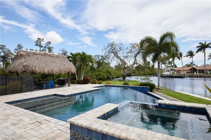 View of swimming pool with a patio area, a water view, and a pool with connected hot tub