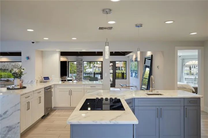 Kitchen with white cabinets, a sink, light stone countertops, and black electric cooktop