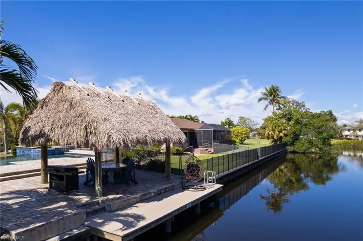Dock area with a water view, a lanai, and a fence