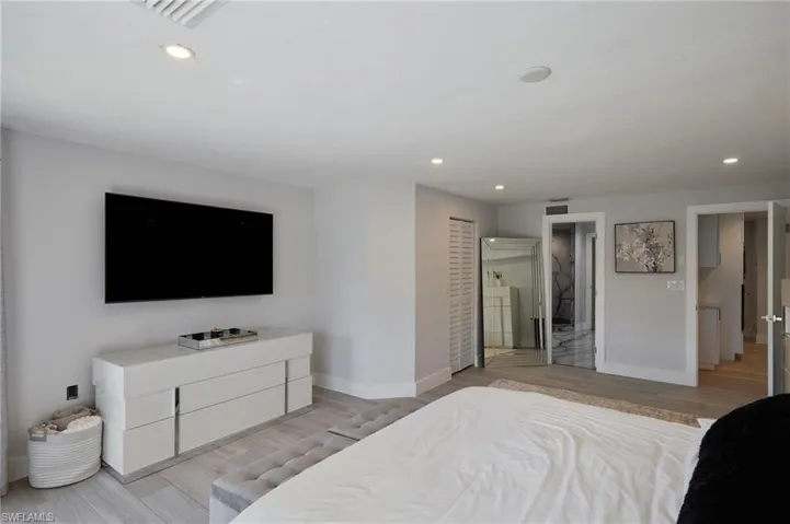 Bedroom with baseboards, recessed lighting, water views finished floors