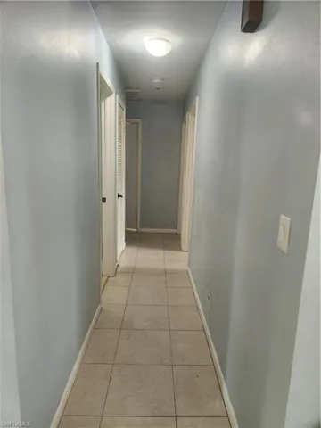 Hallway with light tile patterned flooring and baseboards