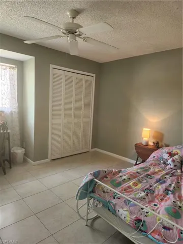 second guest bedroom featuring a ceiling fan, a textured ceiling, and light tile patterned floors