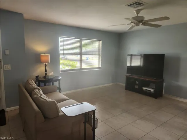 Open living room with ceiling fan and light tile patterned floors