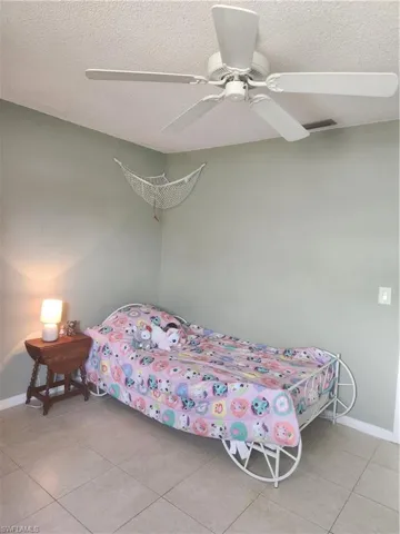 second guest bedroom featuring a ceiling fan, a textured ceiling, and light tile patterned floors
