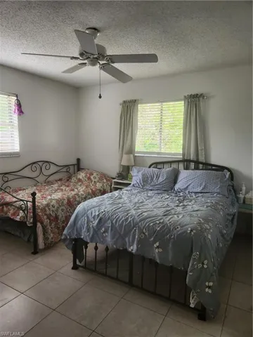 Spacious master bedroom with a textured ceiling and ceiling fan