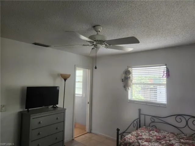 Master bedroom suite with a textured ceiling, a ceiling fan, and light tile patterned flooring