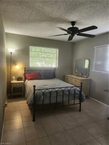 Guest Bedroom featuring a textured ceiling, a ceiling fan, and tile patterned flooring