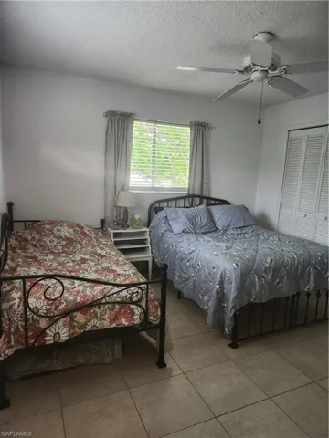 Spacious master bedroom with a textured ceiling and ceiling fan