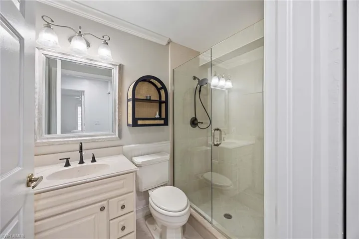 Bathroom featuring crown molding, vanity, and a shower stall