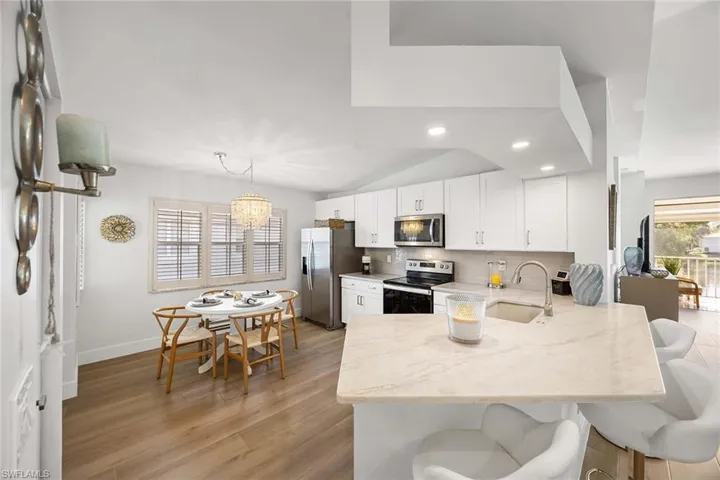Kitchen featuring a peninsula, white cabinetry, a breakfast bar, appliances with stainless steel finishes, and vaulted ceiling