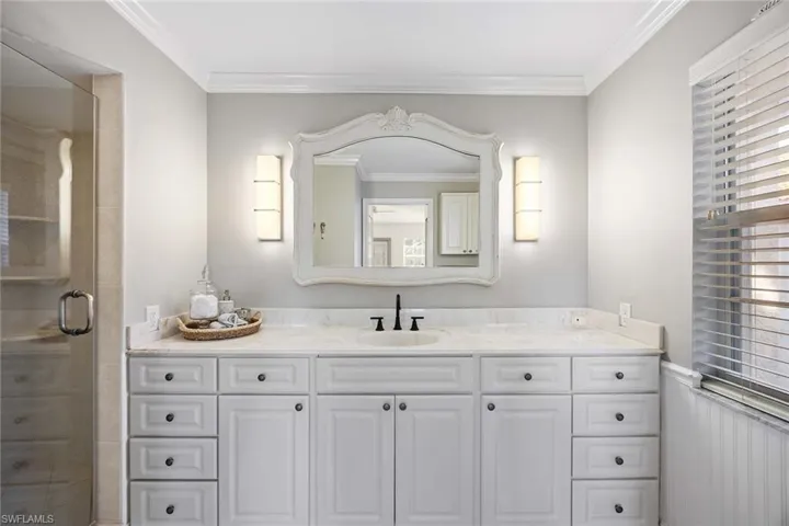 Full bathroom with vanity, crown molding, a stall shower, and wainscoting