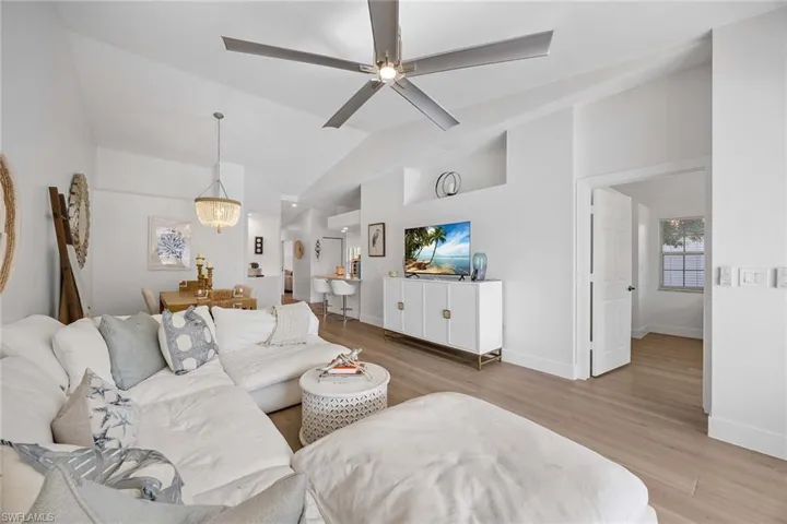 Living room featuring light wood-type flooring, ceiling fan, and vaulted ceiling