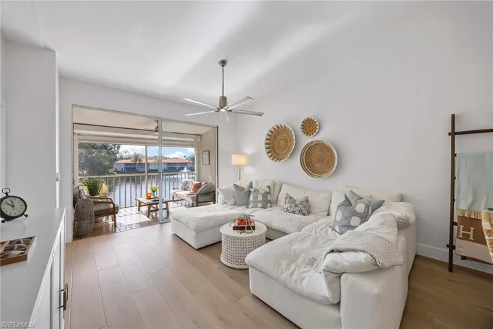 Living area with a water view, light wood-style floors, ceiling fan, and vaulted ceiling