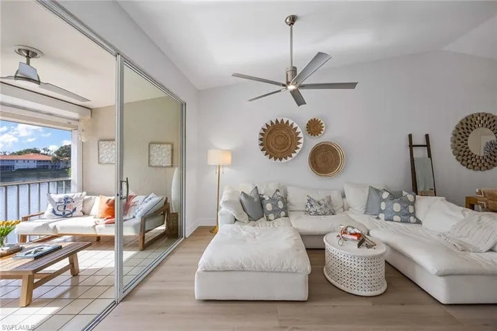 Living room with light wood-style flooring, ceiling fan, a water view, and vaulted ceiling
