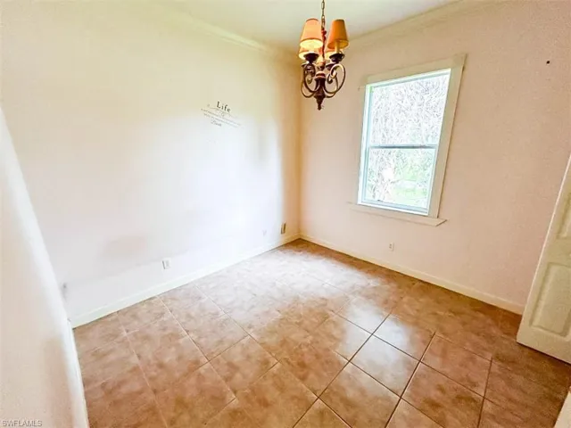 Unfurnished room featuring crown molding and an inviting chandelier