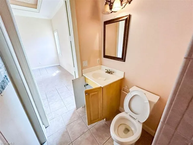 Bathroom featuring toilet, tile patterned floors, an inviting chandelier, vanity, and crown molding