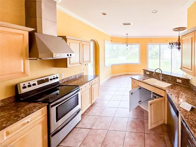 Kitchen with ventilation hood, appliances with stainless steel finishes, a notable chandelier, pendant lighting, and sink