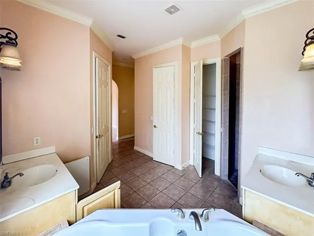 Bathroom featuring vanity, a tub, tile patterned flooring, and ornamental molding