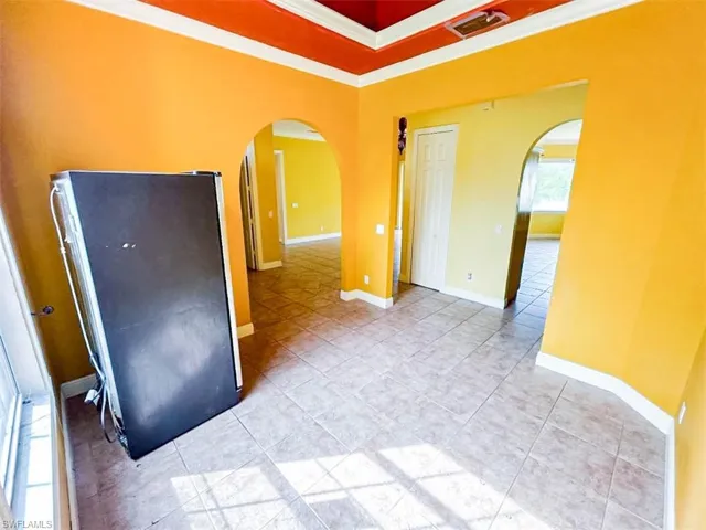 Empty room with ornamental molding and light tile patterned floors