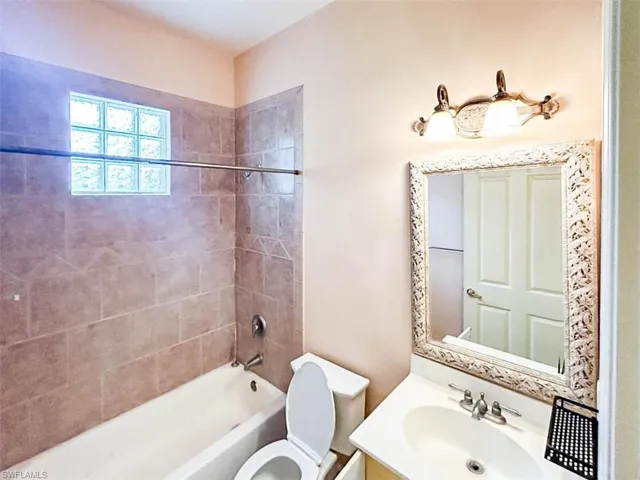 Full bathroom with vanity, tiled shower / bath, and toilet