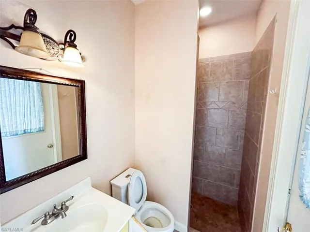 Bathroom featuring toilet, vanity, and a tile shower