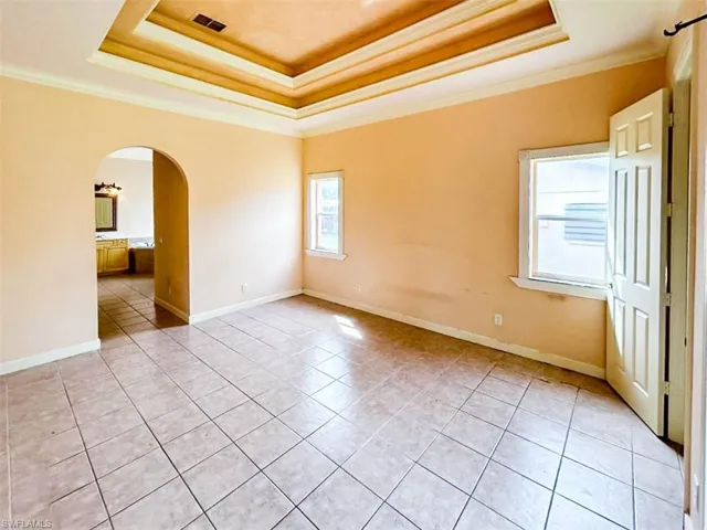 Spare room with ornamental molding, light tile patterned flooring, and a raised ceiling