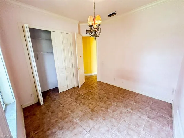 Unfurnished bedroom featuring a chandelier and crown molding