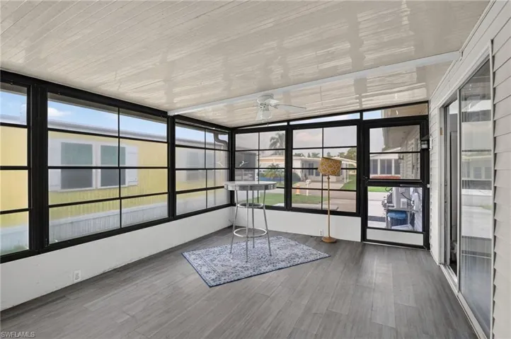 Enclosed sunroom featuring a ceiling fan, wall-to-wall windows with black frames, and wood-finish flooring
