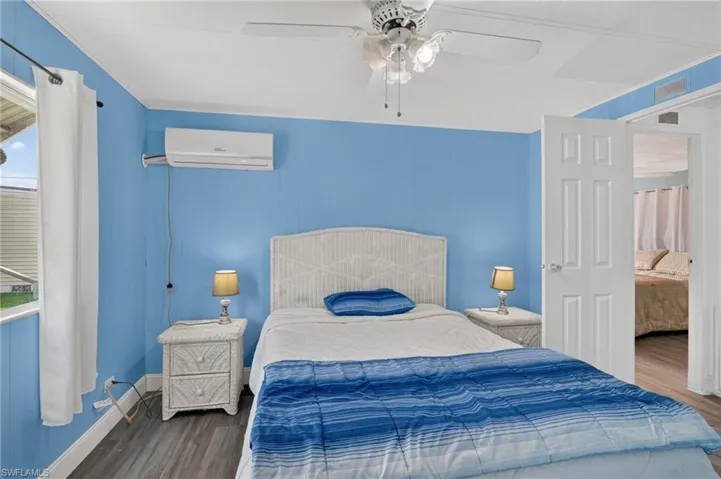 Bedroom featuring wood-finish flooring, a ceiling fan, and a mini-split air conditioning unit