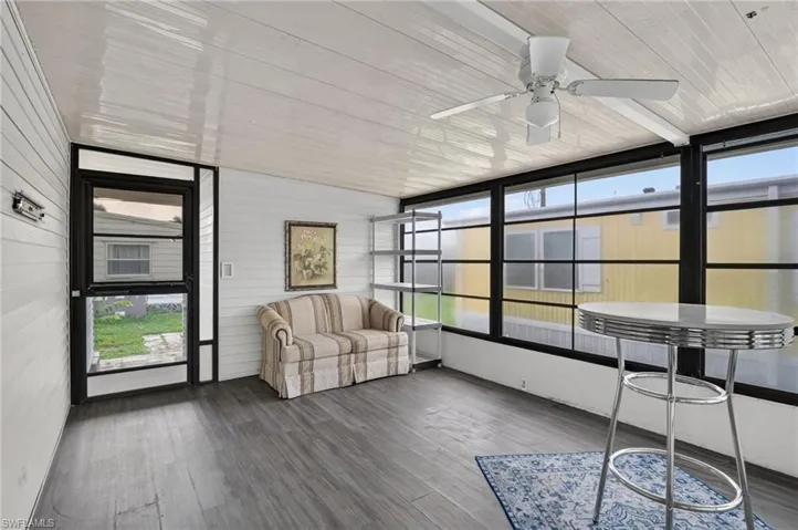 Enclosed patio featuring wood-finish flooring, white paneled walls, and a white ceiling with a ceiling fan