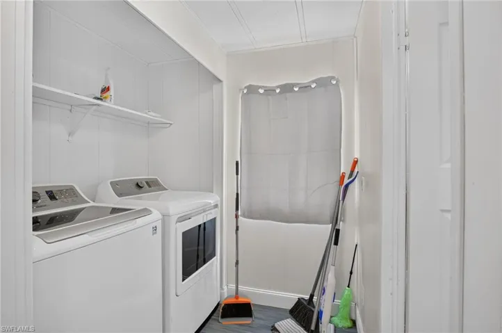 Dedicated laundry area featuring a washer and dryer, an overhead shelf for storage, paneled walls, and wood-finish flooring